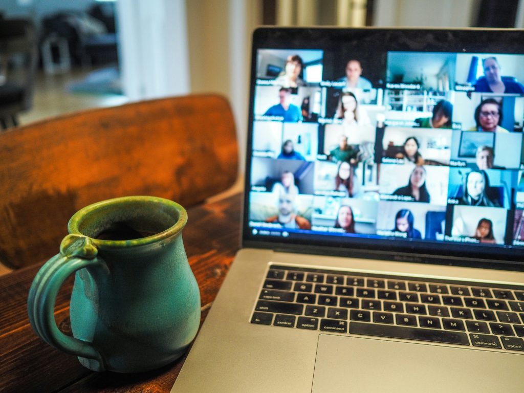 Egy éppen folyó webinár egy laptop képernyőjén sok ember részvételével, bal oldalt egy bögrével